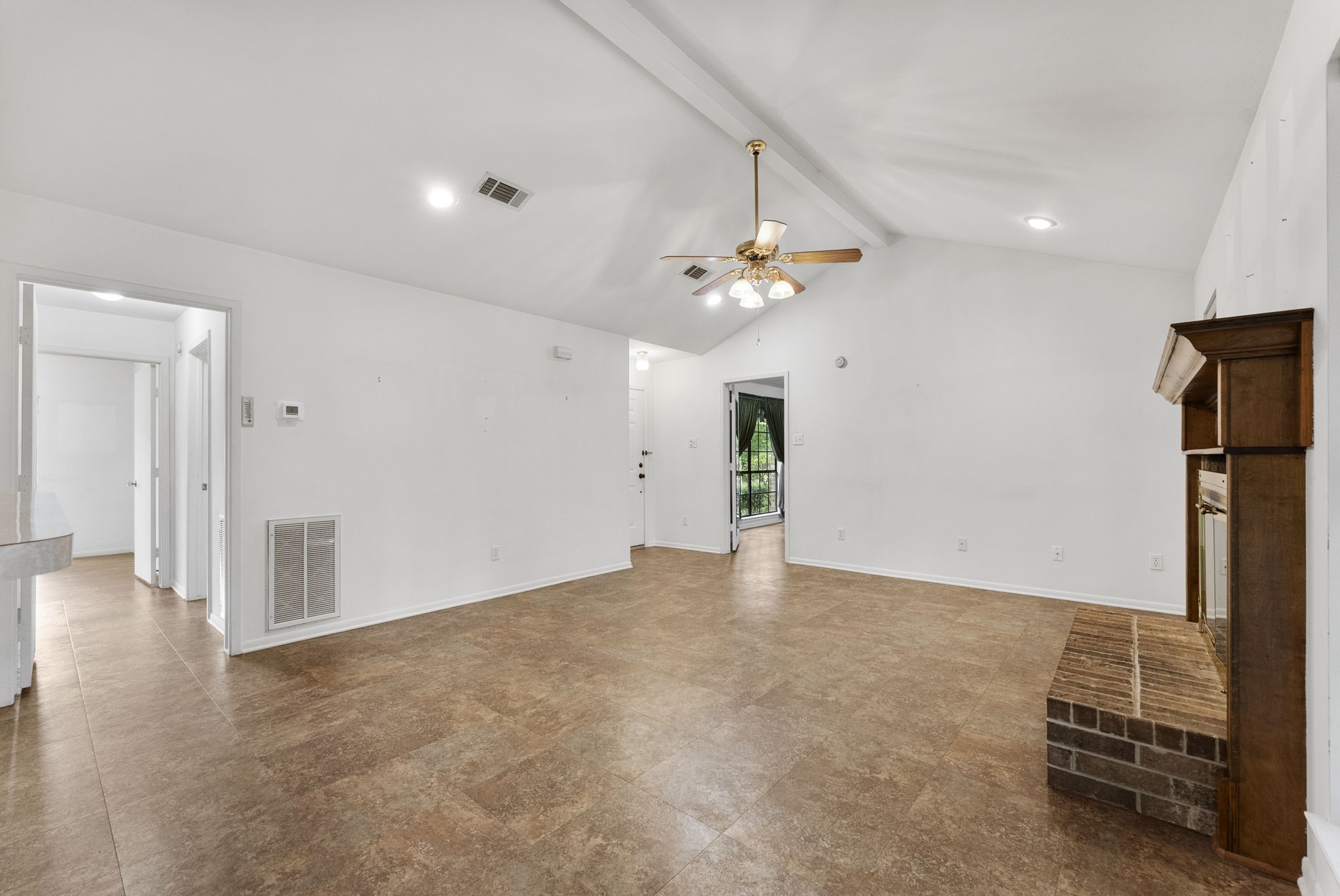202 Sunset Boulevard Conroe, TX 77303 - Photo 12 of 50 This inviting family room features vaulted ceilings, a cozy brick fireplace, and ample natural light, creating the perfect space for relaxation and gatherings.