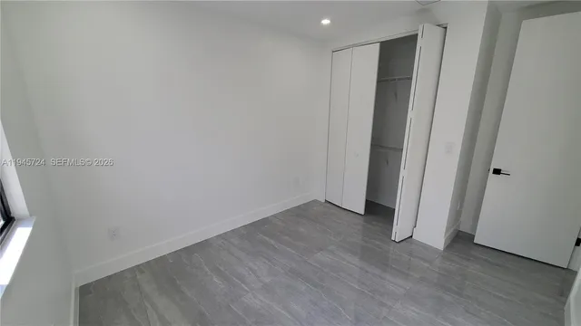 a view of an empty room with wooden floor and closet