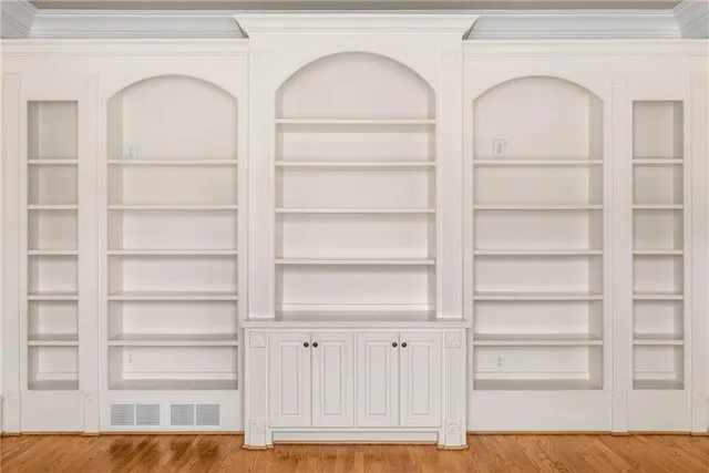 a view of an empty room with wooden floor fridge and a window