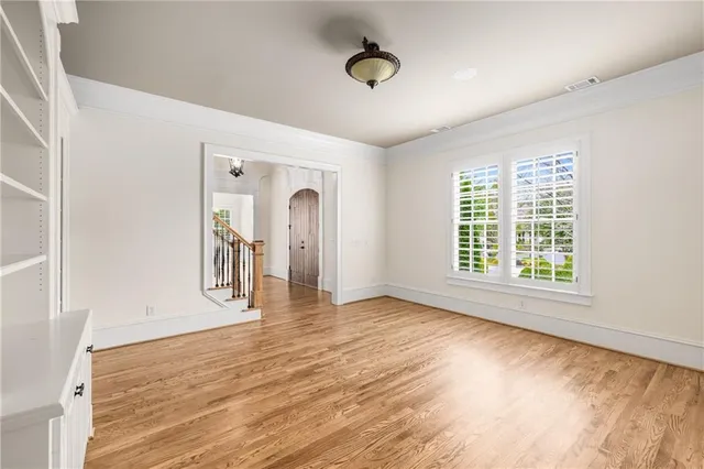 a view of an empty room with wooden floor and a kitchen