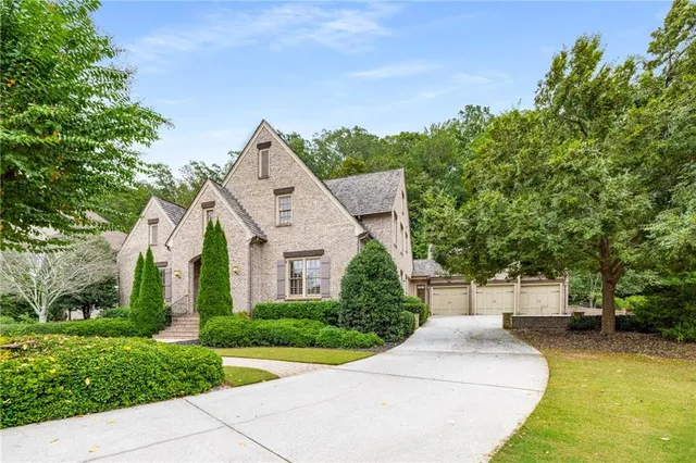 a view of a white house next to a yard with big trees