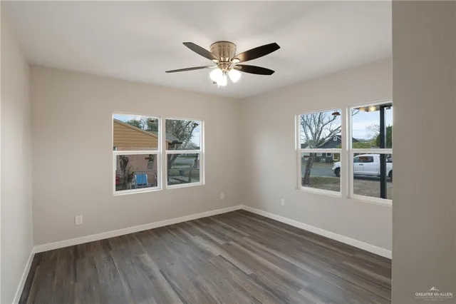 a view of empty room with wooden floor and fan