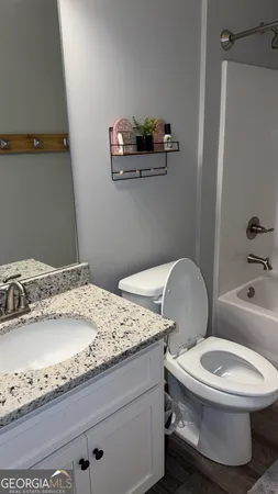 a bathroom with a granite countertop toilet sink and mirror