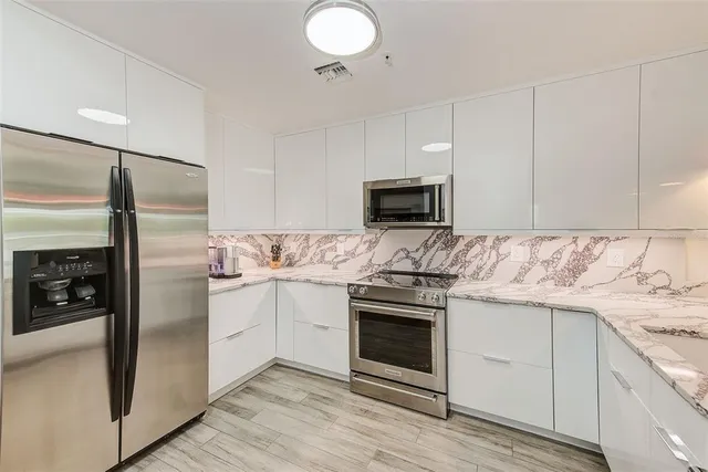 a kitchen with stainless steel appliances kitchen island granite countertop a refrigerator and a stove top oven