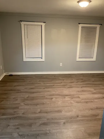 a view of an empty room with window and wooden floor