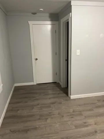 a view of an empty room with wooden floor and closet