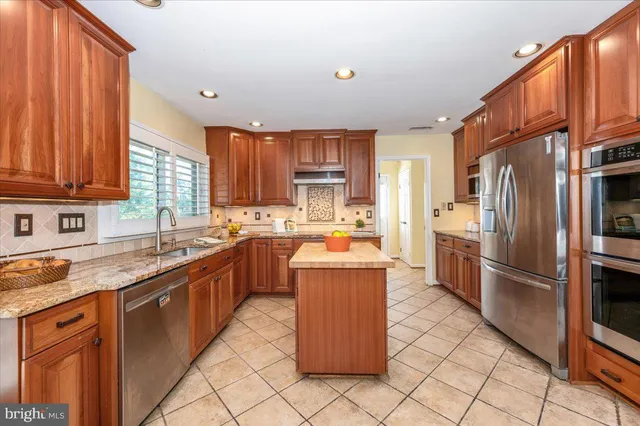 a kitchen with stainless steel appliances granite countertop a stove a sink dishwasher a refrigerator and cabinets with wooden floor