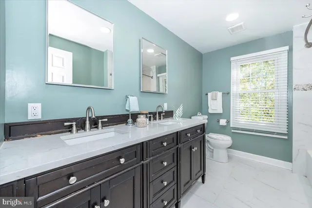 a bathroom with a granite countertop sink a toilet and a mirror