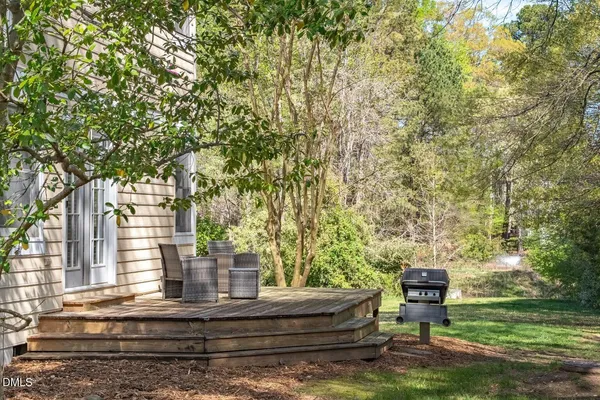 a backyard of a house with large trees and outdoor seating