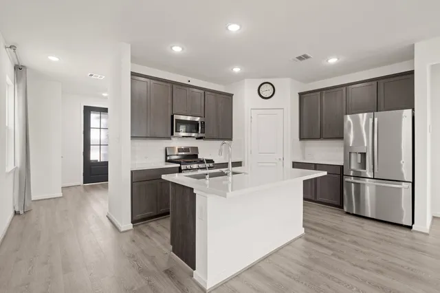 a kitchen with stainless steel appliances a refrigerator a stove top oven and sink