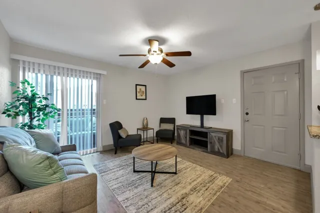 a living room with furniture a flat screen tv and a large window