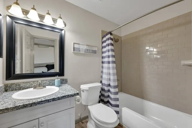 a bathroom with a granite countertop sink toilet a mirror and shower