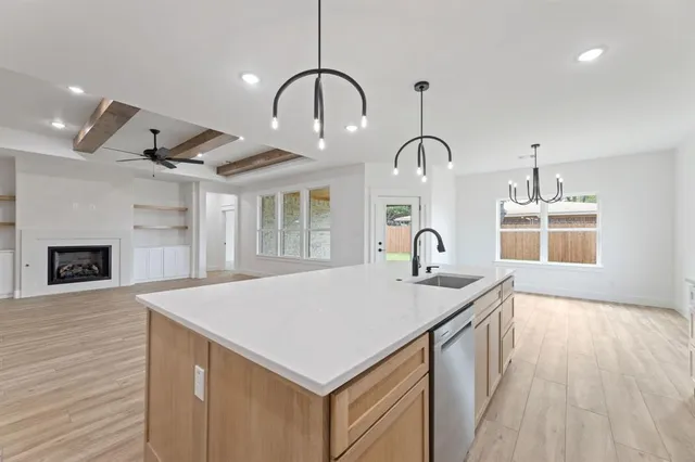a living room with kitchen island a sink and a stove with wooden floor