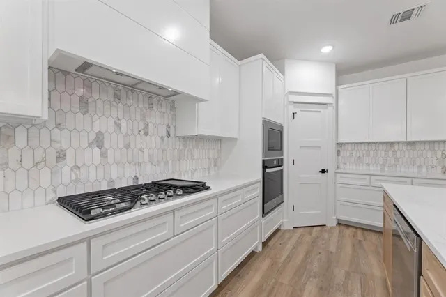 a kitchen with white cabinets and appliances