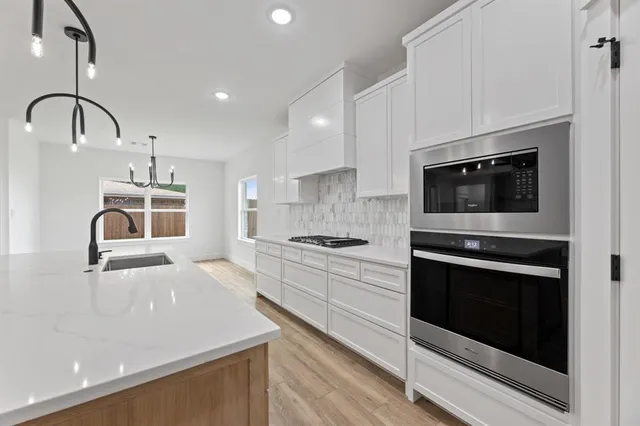 a kitchen with granite countertop white cabinets and stainless steel appliances