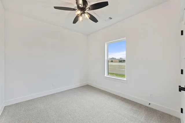 an empty room with a window and a fan