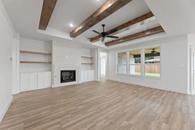 an empty room with wooden floor fireplace and windows