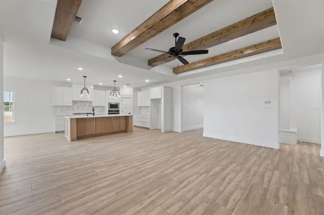 a view of a kitchen with kitchen island a sink wooden floor and appliances