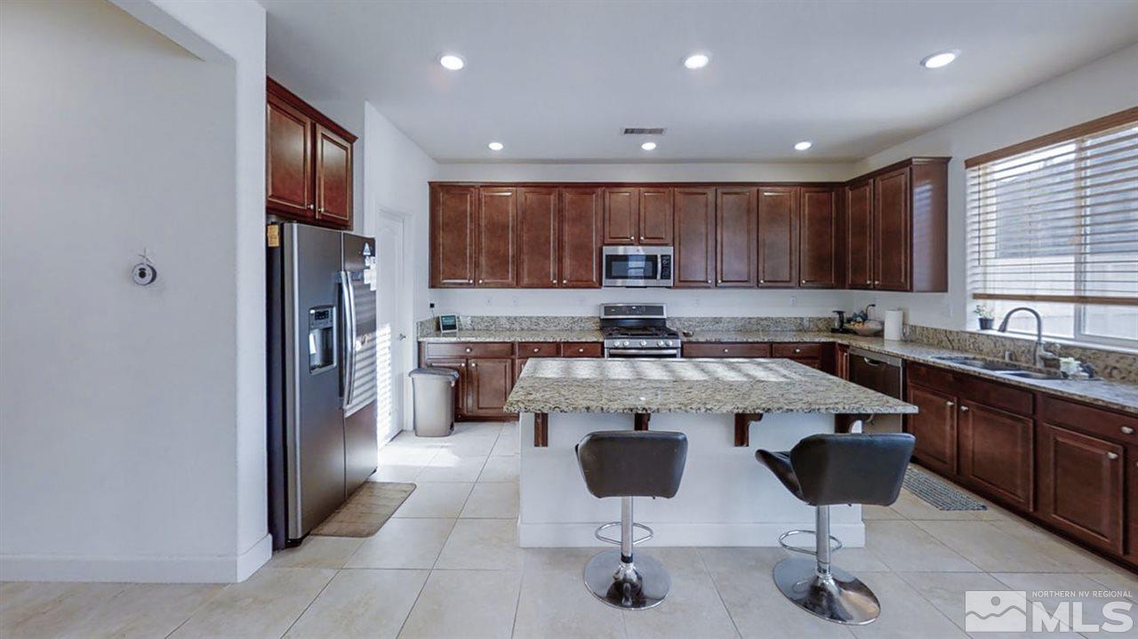 9715 Pachuca Drive Reno, NV 89521 - Photo 3 of 10 a kitchen with stainless steel appliances granite countertop a refrigerator and a stove top oven