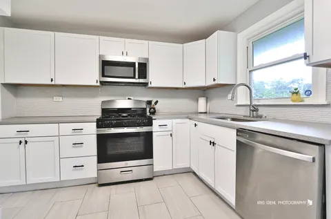 a kitchen with white cabinets and appliances