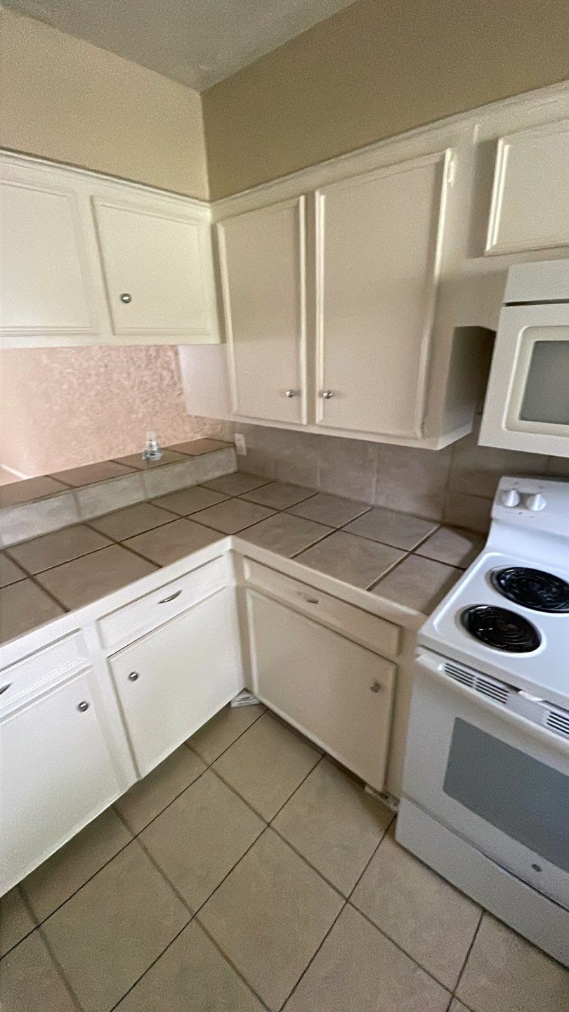 1305 Adams Street, Unit 4 Conroe, TX 77301 - Photo 22 of 32 a kitchen with a stove and white cabinets