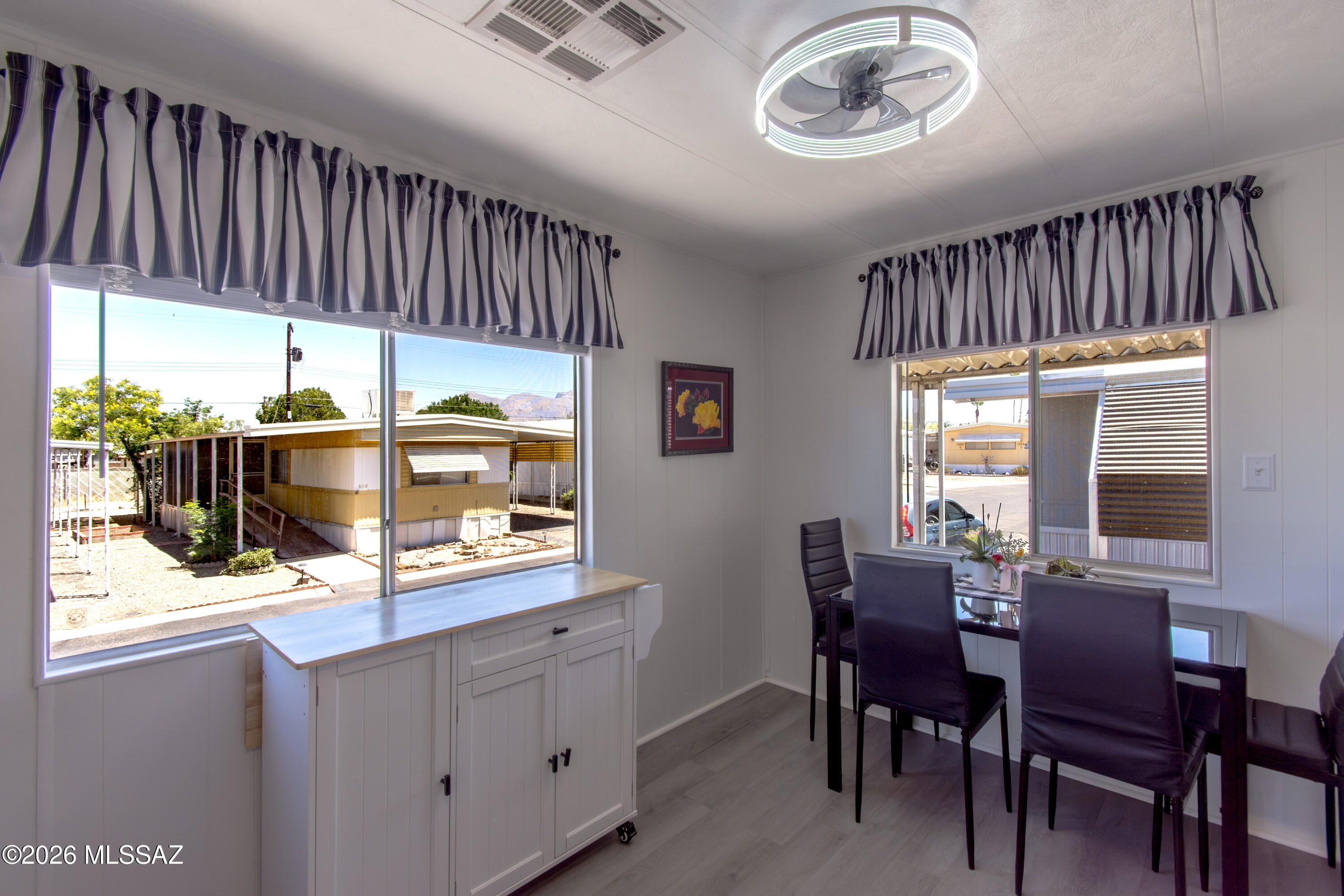 4550 North Flowing Wells Road, Unit 155 Tucson, AZ 85705 - Photo 14 of 40 a dining room with wooden floor a glass table and chairs