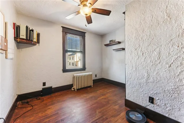 a view of an empty room with a window and wooden floor