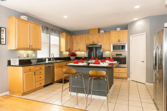 a kitchen with a refrigerator and a stove top open