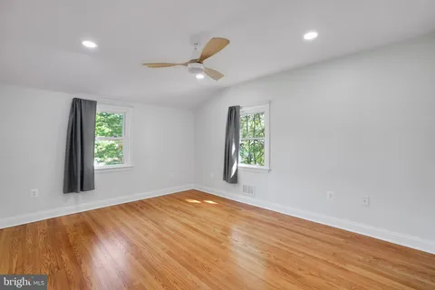 an empty room with a chandelier fan and bathroom view