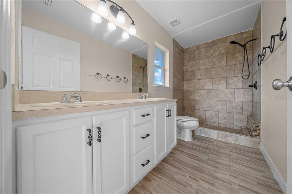 12205 Southeast 100th Court Belleview, FL 34420 - Photo 32 of 73 a spacious bathroom with a double vanity sink a toilet and a mirror