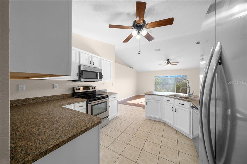 12205 Southeast 100th Court Belleview, FL 34420 - Photo 37 of 73 a kitchen with stainless steel appliances granite countertop a sink stove and refrigerator