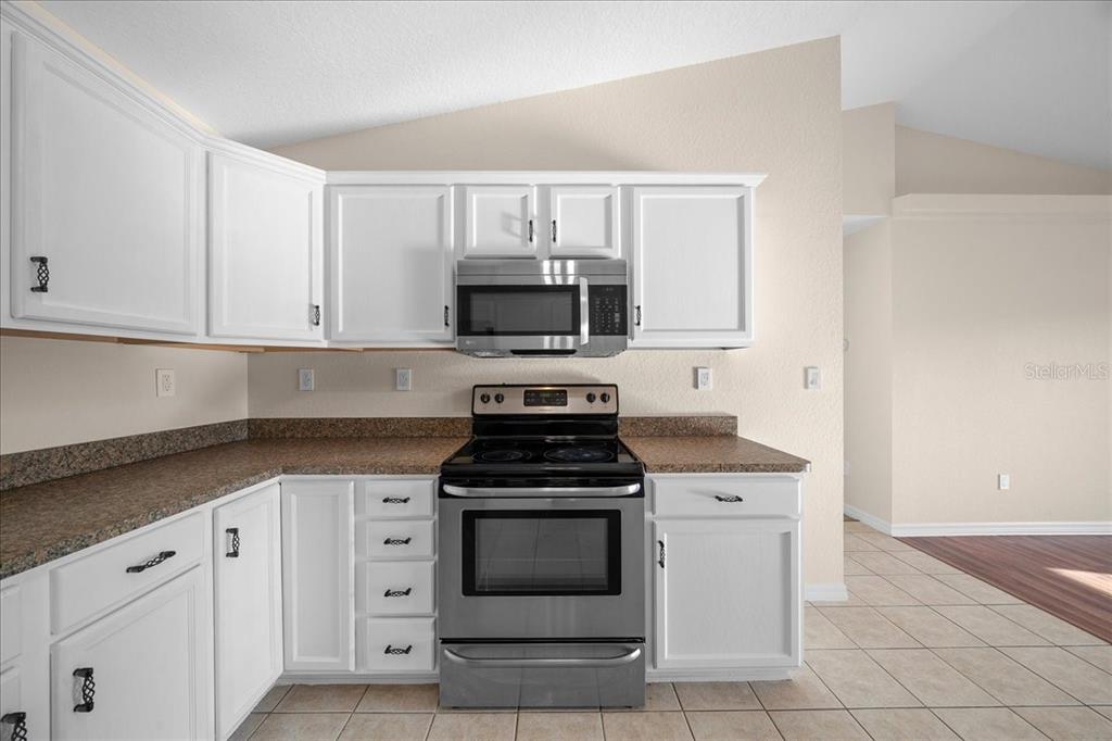 12205 Southeast 100th Court Belleview, FL 34420 - Photo 38 of 73 a kitchen with white cabinets and stainless steel appliances