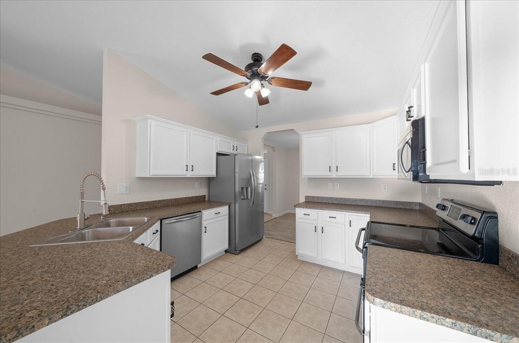 12205 Southeast 100th Court Belleview, FL 34420 - Photo 43 of 73 a kitchen with stainless steel appliances granite countertop a sink a stove and a refrigerator