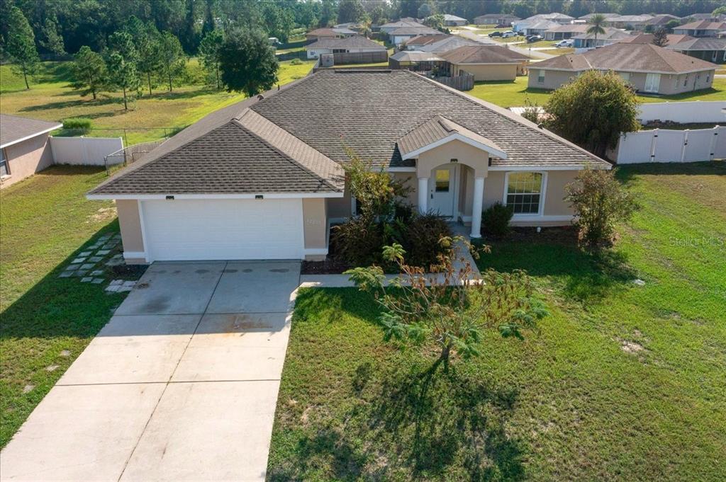 12205 Southeast 100th Court Belleview, FL 34420 - Photo 72 of 73 a aerial view of a house with swimming pool lawn chairs and a yard with lake view