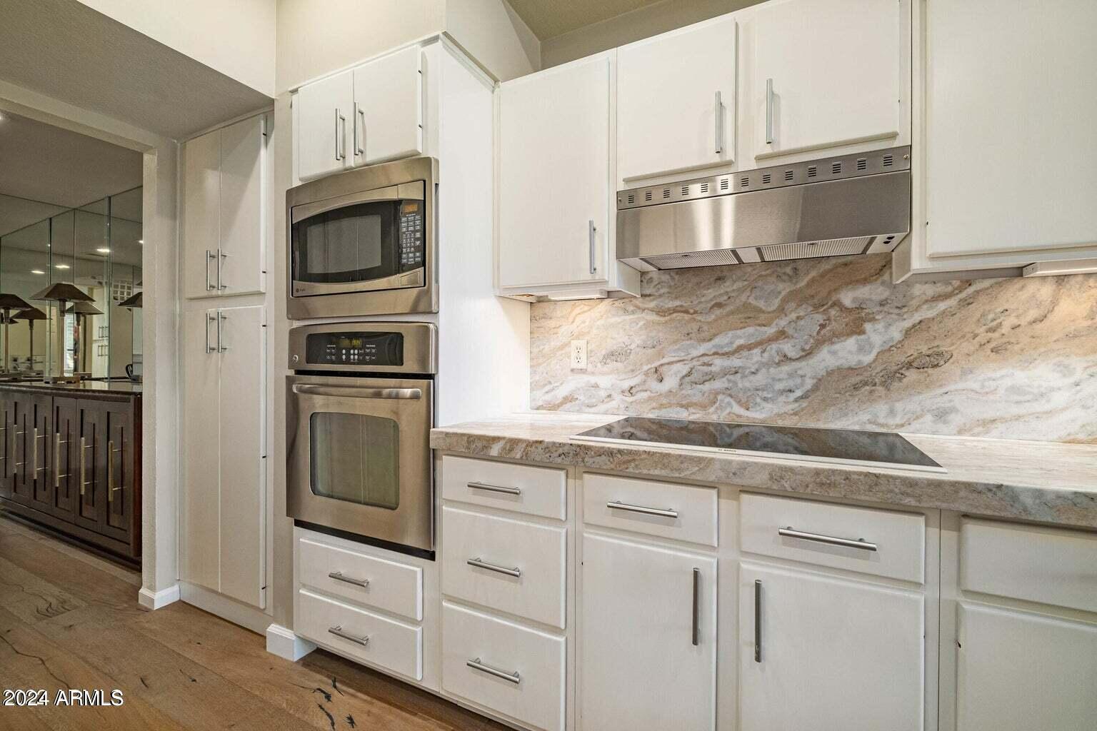 7272 East Gainey Ranch Road, Unit 43 Scottsdale, AZ 85258 - Photo 9 of 40 a kitchen with granite countertop white cabinets and stainless steel appliances