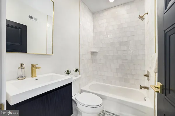 a bathroom with a sink a toilet a mirror and shower