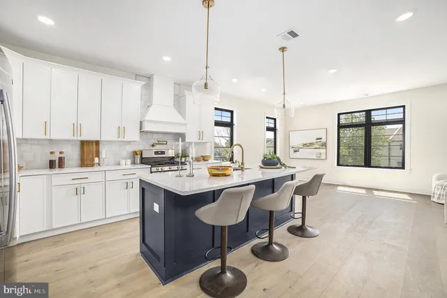 a kitchen with stainless steel appliances granite countertop a sink a stove and a wooden floors