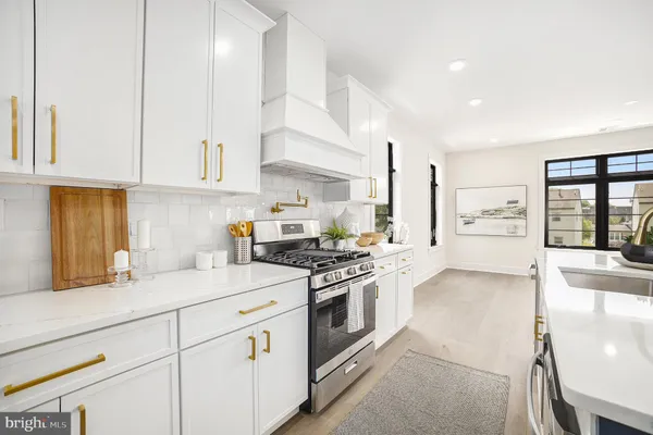 a kitchen with stainless steel appliances granite countertop a stove a sink and white cabinets