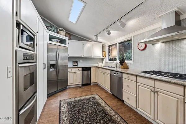 a kitchen with stainless steel appliances granite countertop a refrigerator a sink and white cabinets