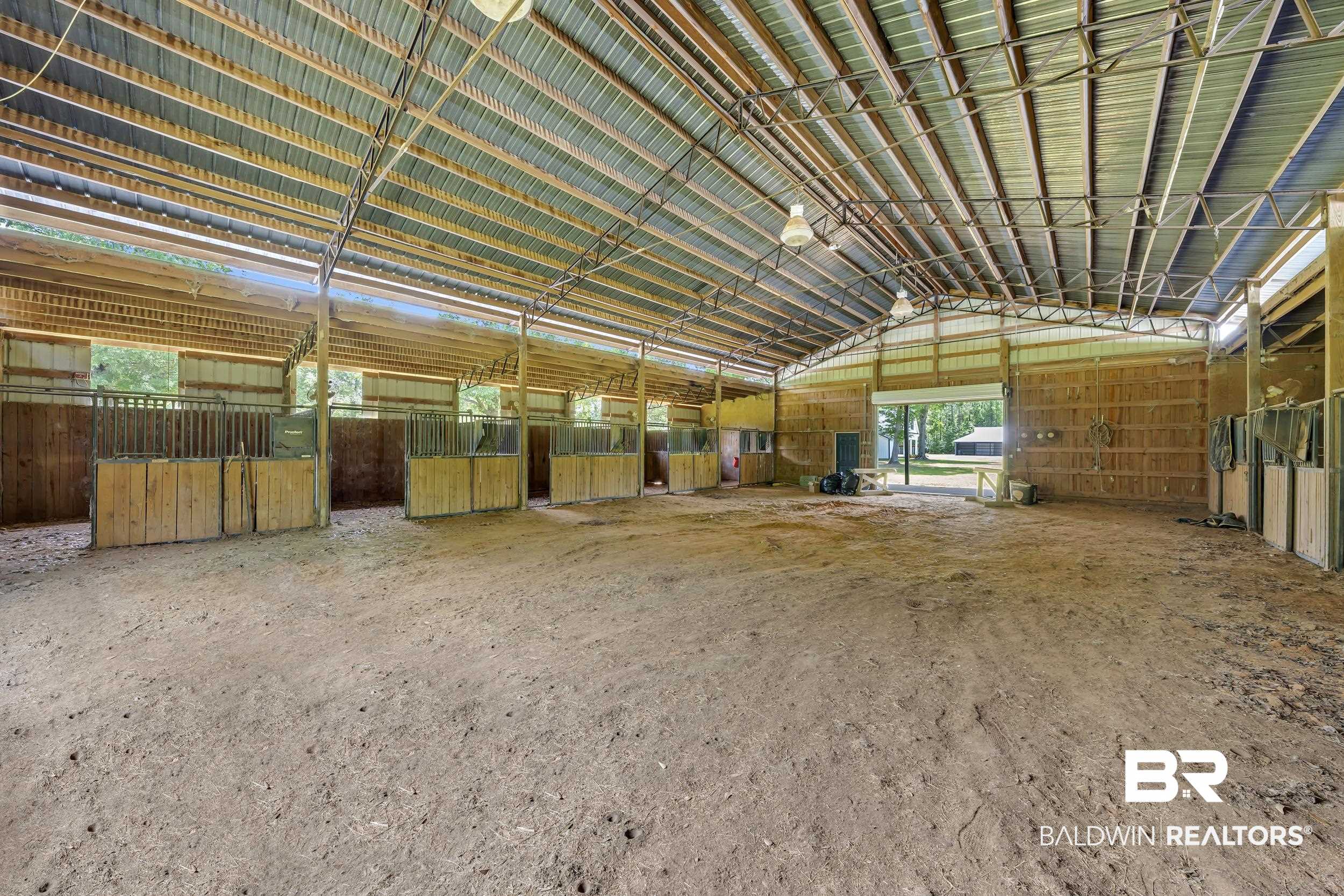 43199 Pine Grove Road Bay Minette, AL 36507 - Photo 20 of 71 Spacious barn structure featuring a corrugated metal roof, exposed metal truss system, and multiple wood-paneled stalls