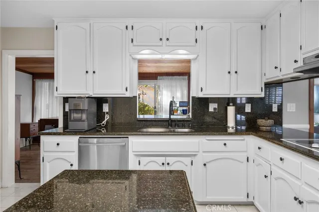 a kitchen with granite countertop a sink a stove and cabinets