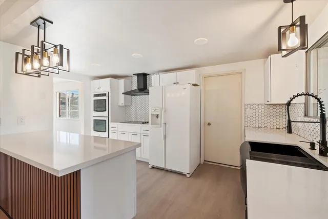 a room with kitchen island stainless steel appliances a sink cabinets and wooden floor