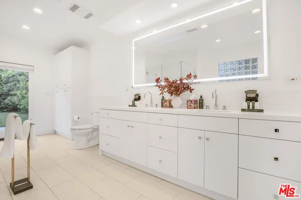 a bathroom with a double vanity sink a toilet and a mirror
