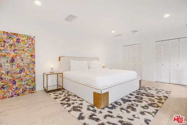 a white bed sitting in a bedroom next to a lamp