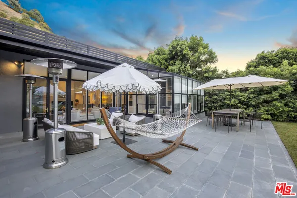a view of a patio with table and chairs potted plants with wooden roof and plants