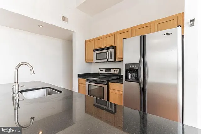 a kitchen with stainless steel appliances granite countertop a refrigerator sink and stove
