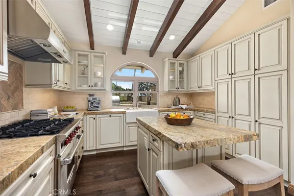 a kitchen with stainless steel appliances a sink a stove a refrigerator cabinets and a dining table