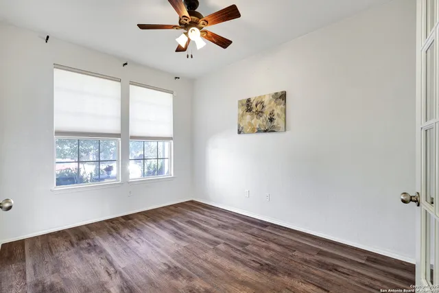 a view of an empty room with a window and wooden floor