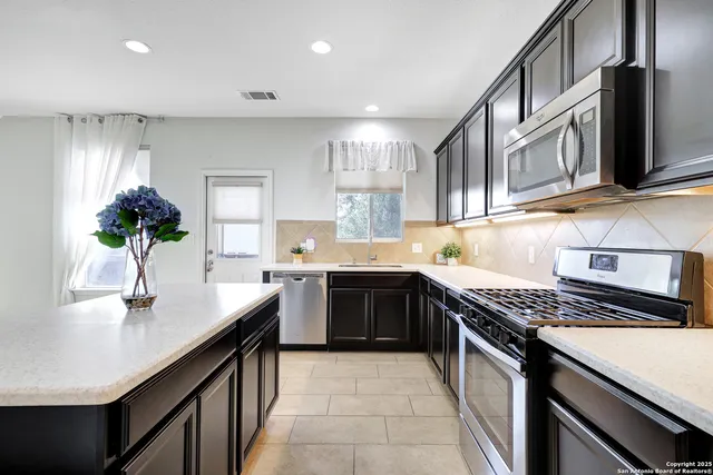 a kitchen with stainless steel appliances granite countertop a sink stove and cabinets