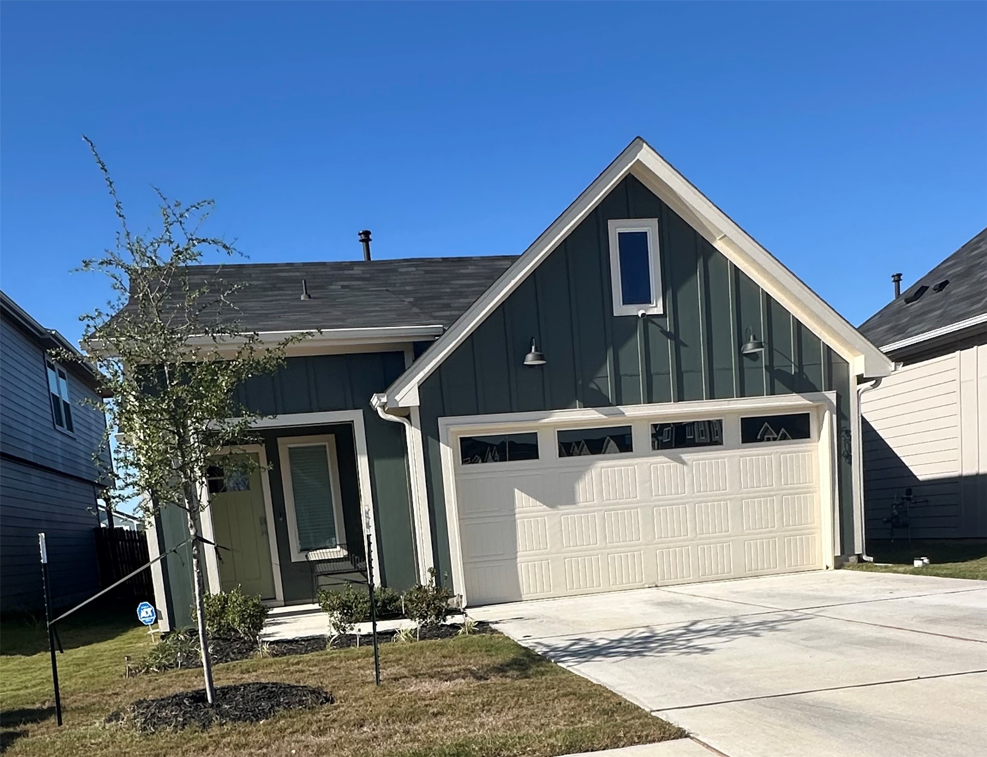 Modern farmhouse with board and batten siding, a garage, concrete driveway, a front yard, and roof with shingles